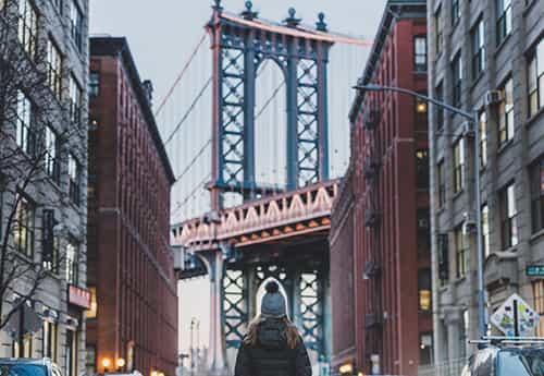 photo of a person walking down an urban street towards a bridge